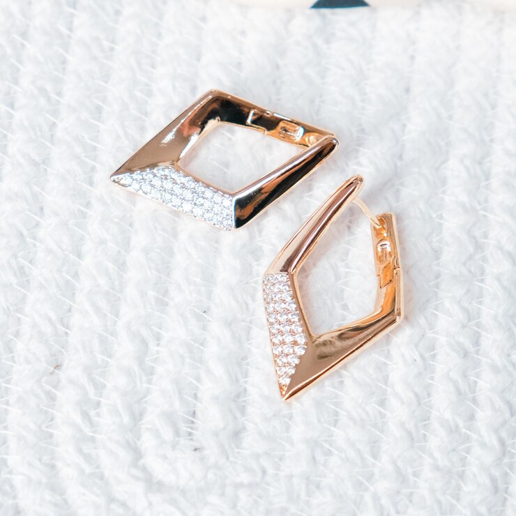 Two diamond earrings are laying on a white surface.