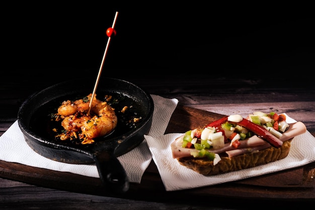 Photo two different and clasical spanish tapas on a rustic table with a dark background traditional spanish cuisine