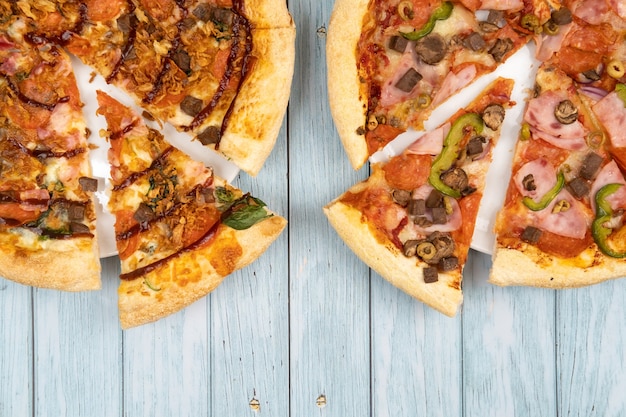 Two different delicious big pizzas on a blue wooden background.