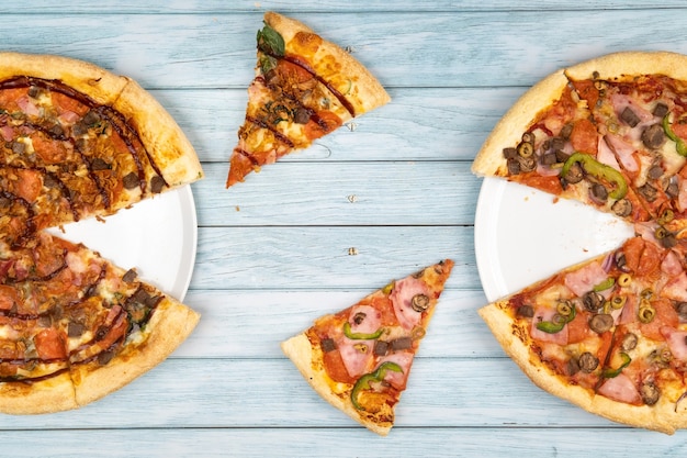 Две разные вкусные большие пиццы на синем деревянном фоне