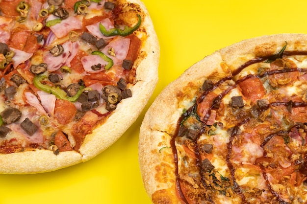 Two different Delicious big pizzas on a yellow background.