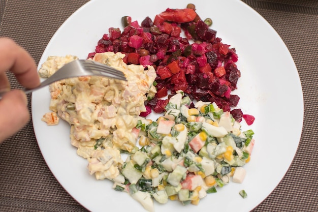 Foto due diverse vinaigrette di insalata e olivier su un piatto bianco