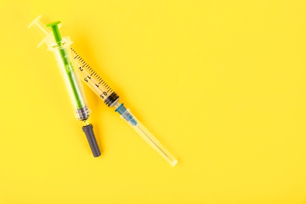 Two disposable syringes on a yellow 