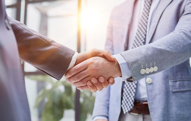 Two diverse professional business men executive leaders shaking hands at office meeting