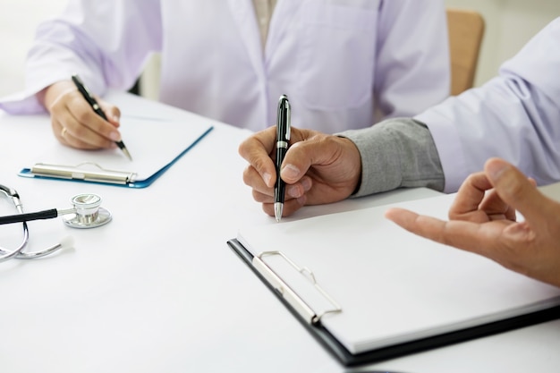 그들은 진단을하거나 치료를 결정할 때 서류와 클립 보드를 가리키는 사무실에서 환자 노트를 논의하는 두 의사