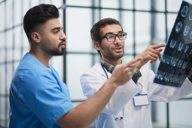 Two doctors examine radiograph for medical xray diagnosis in sterile room