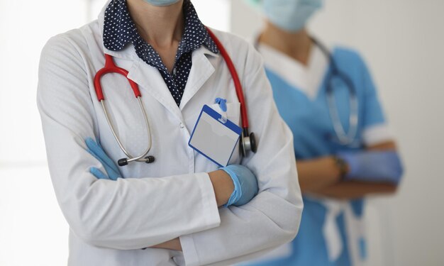 Two doctors in gloves and white coats stand with folded arms