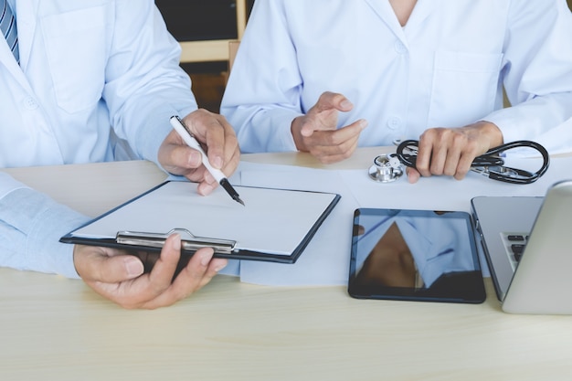 Two doctors have a discussion sitting at desk in the hospital