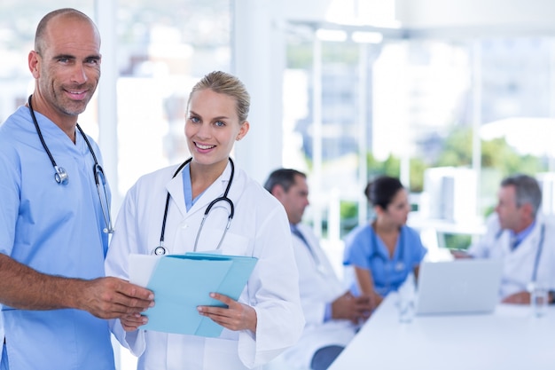 Two doctors holding clipboard while their colleagues working 