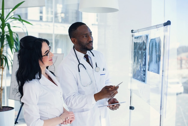 Two doctors look at an x-ray and discuss the problem. Medical technicians pointing at MRI x-ray of patient. Radiologist checking x-ray. Medical and radiology concept.