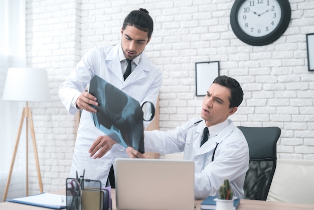 Two doctors look at the x-ray in the medical office.