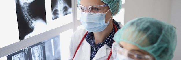 Two doctors in medical protective masks examining medical xrays