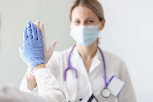 Two doctors in protective masks and gloves give each other five