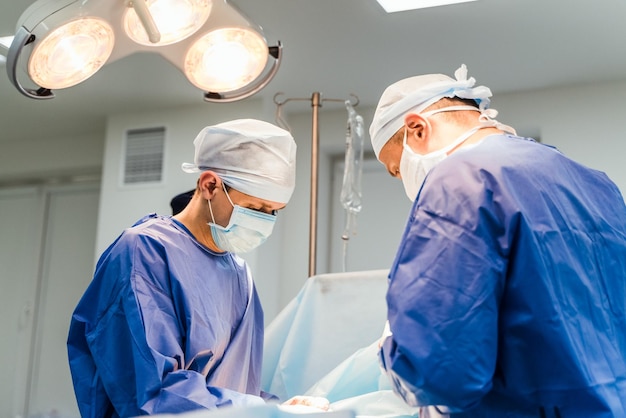 Two doctors in sterile medical clothes perform an operation in a hospital Professional work in the clinic Health concept medicine close up