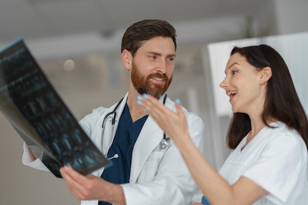 Two doctors in uniform look and discuss an xray or mri scan of the patient spine