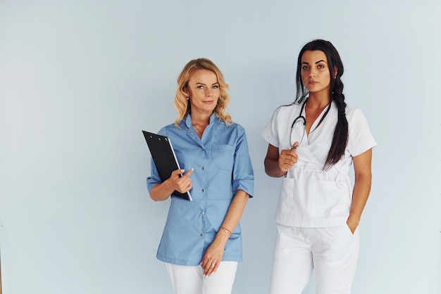 Photo two doctors in uniform standing indoors and working together