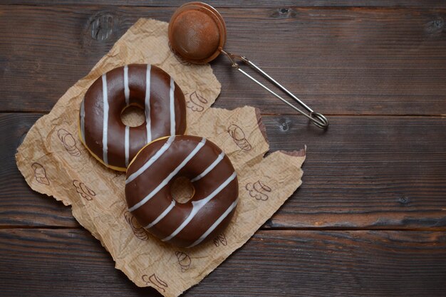 Two donuts in chocolate glaze on a wooden background flat lay