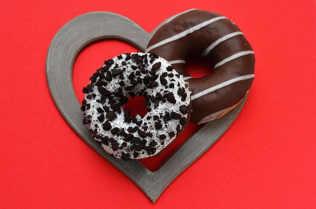 Two donuts in a heartshaped frame on a red background