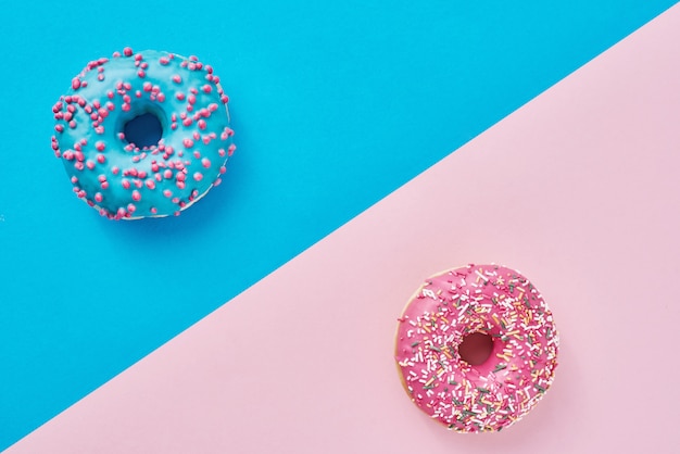 파스텔 핑크와 파란색 배경에 두 도넛입니다. 미니멀리즘 창의적인 음식 구성. 평평한 스타일