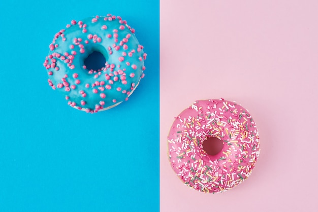 Two donuts on pastel pink and blue. Minimalism creative food composition. Flat lay style