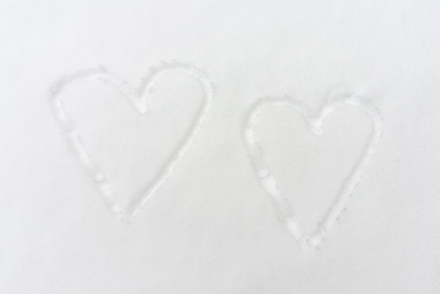 Photo two drawn hearts in the snow top view