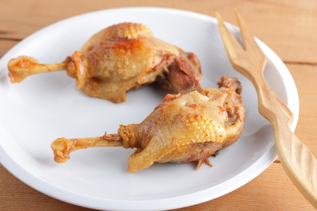 Two duck legs on a white plate on a wooden background Baked duck with spices closeup