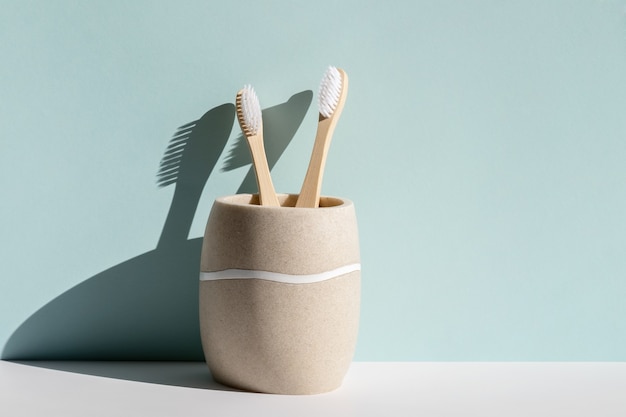 Two eco friendly bamboo wooden toothbrushes in a glass on a blue background Hard light