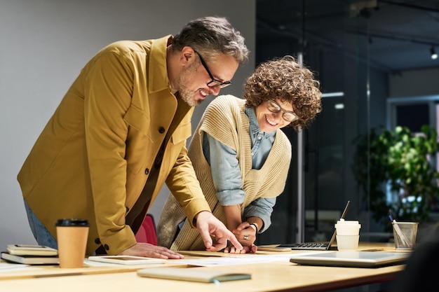 Two economists bending over workplace while one of them explaining data