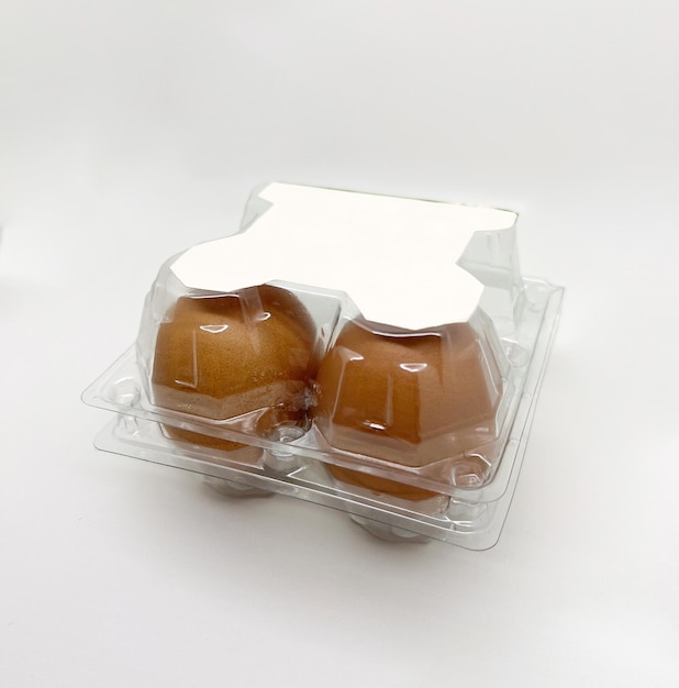 Two eggs in a plastic container on a white surface.