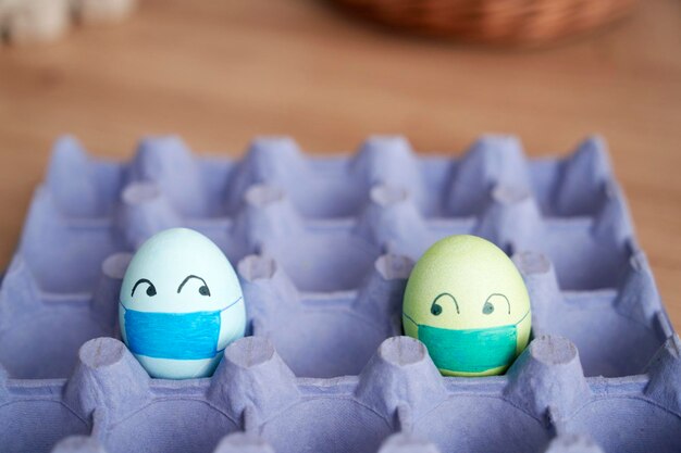 Two eggs with face masks in a cardboard box