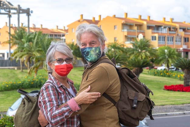 Foto due anziani in giro per la città che indossano una maschera chirurgica a causa del coronavirus