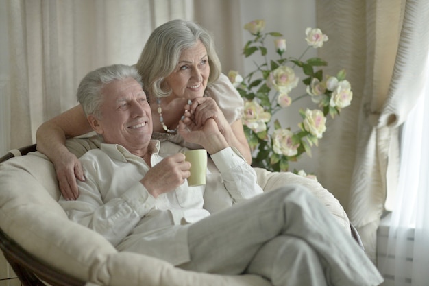 Two elderly people sitting near couch with tea