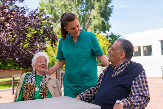 Two elderly people with the nurse in the garden of a nursing home or retirement home old man and old woman