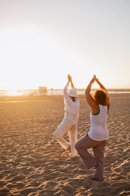 Two elderly women doing yoga on the beach