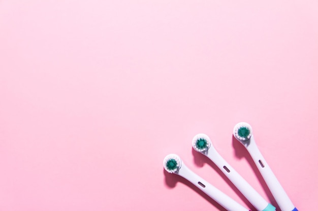 Two electrical toothbrushes on a soft light pink background