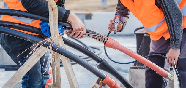 Two electrician builder workers installing highvoltage cable