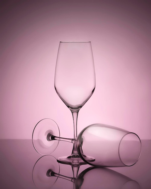 赤ピンクの背景に 2 つのエレガントな空のワイングラス反射輪郭ミニマルな静物