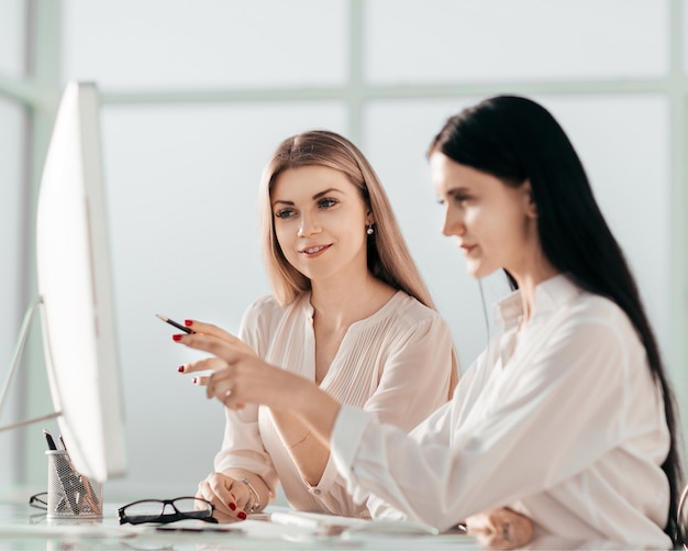 Two employees are discussing something sitting at the office table. office weekdays