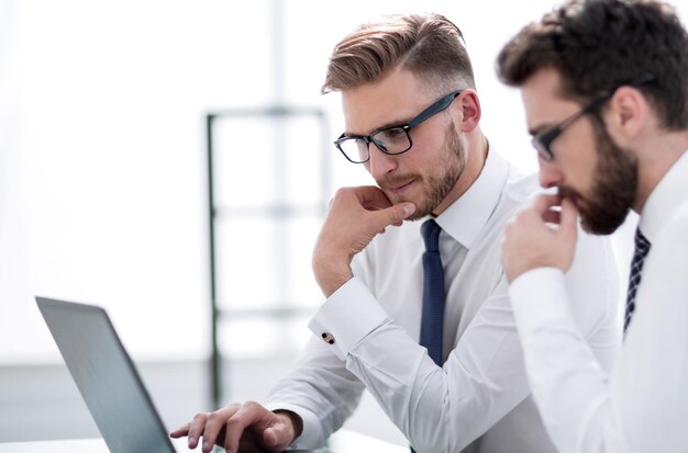 Two employees use a laptop while sitting at their Deskthe concept of professionalism