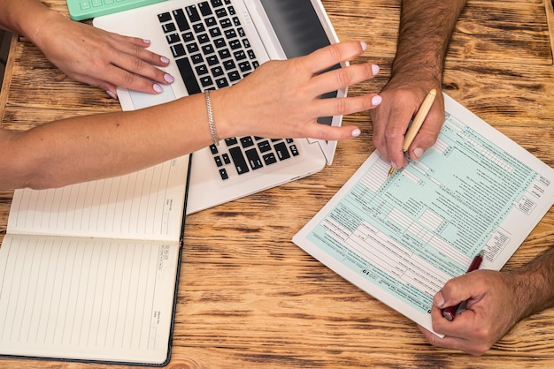 Two employees at work fill out tax forms 1040 at the office\
desk