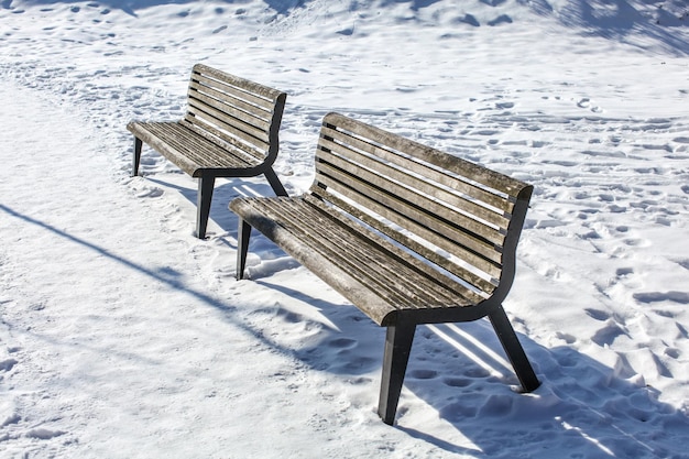 Two empty benches on snow covered ground