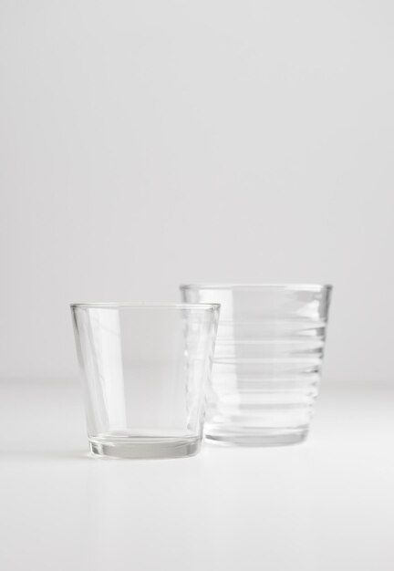 Two empty clear glasses on white background