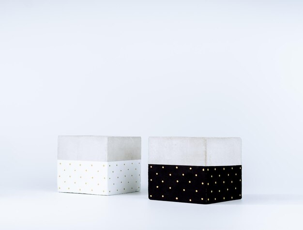 Two empty DIY painted concrete planters isolated on white background with copy space. The cubic shape of the modern black and white cement plant pots is painted with gold dots.