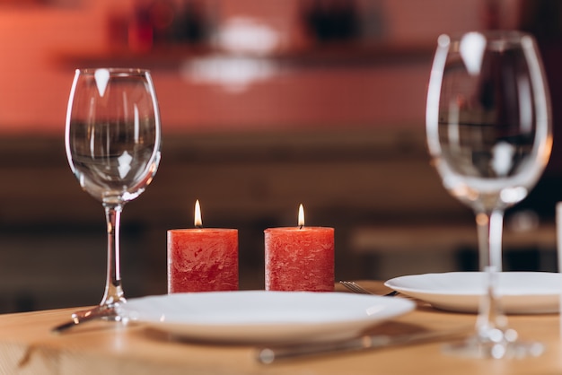 Two empty glasses and burning candles on a served table close-up