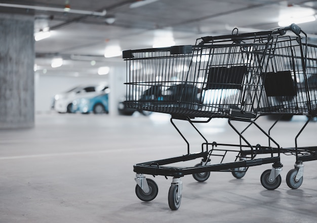 Photo two empty shopping cart and blurred car at parking lot, winter color tone