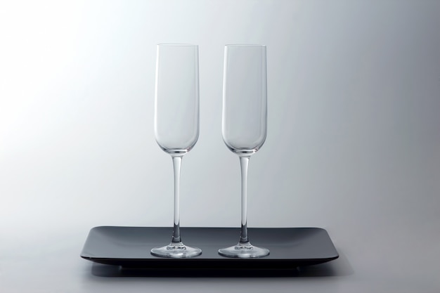 Two empty wine glass on a brown plate on light