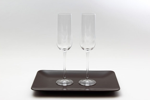 Two empty wine glass on a brown plate on light