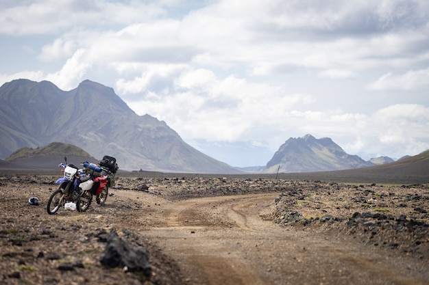 Due moto enduro in piedi su una strada sterrata nel deserto circondato da montagne sul sentiero laugavegur, islanda. concetto di viaggio fuoristrada, equipaggiamento per motociclisti enduro, stile di vita estremo.