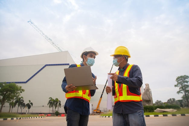 Two Engineer working computer technology on site construction, Two Engineer wear mask protect covid19