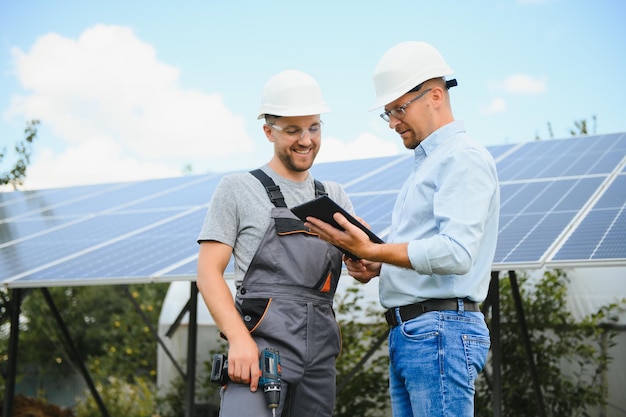 Two engineers are conducting outdoor inspection of solar photovoltaic panels